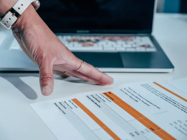 Close-up of a hand reviewing a financial report on a laptop, indicating focus on business analysis. Så förhandlar du fraktavtal med transportörer